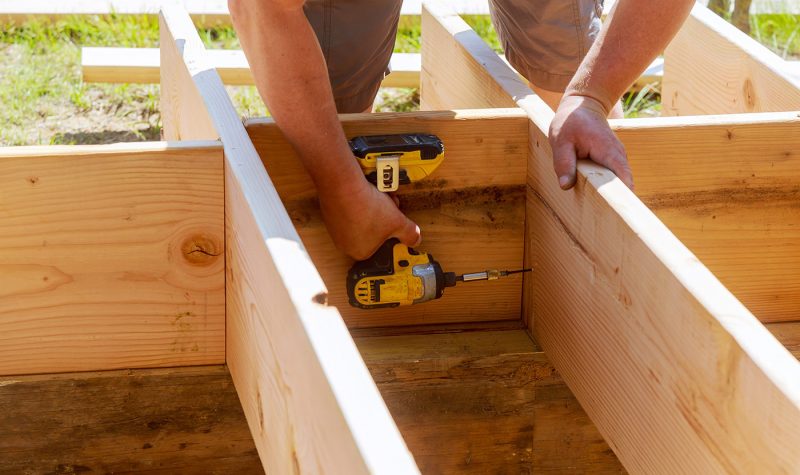 full-length-of-carpenter-drilling-wood-at-construc-2021-08-31-05-08-02-utc